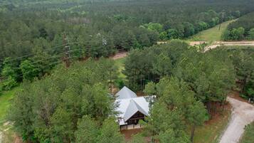 A cabin surrounded by dense forest, with a dirt road leading to it.