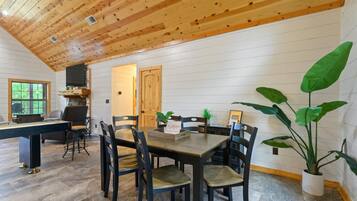A dining area with a wooden ceiling, white walls, and a large potted plant.
