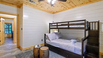 Une chambre avec un lit superposé, un ventilateur de plafond, des murs en bois et une fenêtre.
