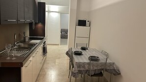 A compact kitchen with a dining area, including a table set for two, a microwave, and a refrigerator. - Casa Teresa (Firenze)