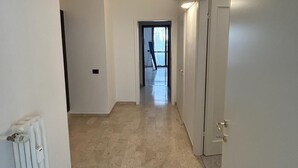 A hallway with a radiator on the left, a door on the right, and a view into another room at the end. - Casa Teresa (Firenze)