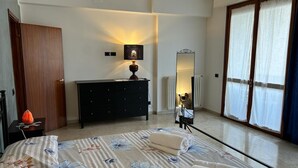A bedroom with a bed, a dresser, a nightstand, a mirror, and a window with curtains. - Casa Teresa (Firenze)
