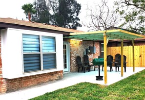 A house with a covered patio area, a brick exterior, and a green lawn.