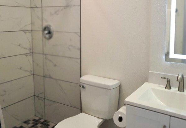 Un baño con inodoro, lavamanos y zona de ducha.