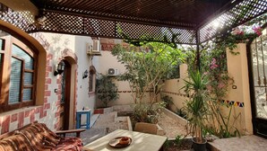 Un espacio de estar techado al aire libre con una mesa, sillas y una planta en maceta.