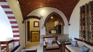 Un amplio salón con techo alto, chimenea y vista a la cocina.