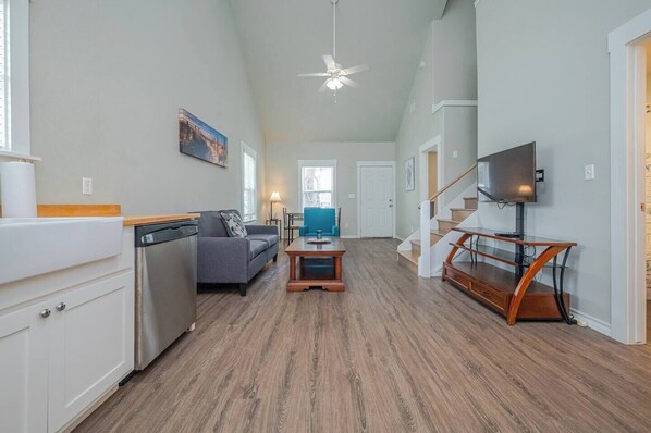 A spacious living area with a kitchen, a dining table, a sofa, and a TV.