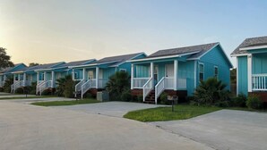 Een rij blauwe gelijkvloerse huizen met voortoeltjes en treden naar de ingang.