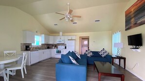 A compact living space with a kitchenette, a dining area, a sofa set, and a television.