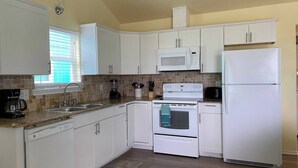 A kitchen with white cabinets, a microwave, a stove, and a refrigerator.