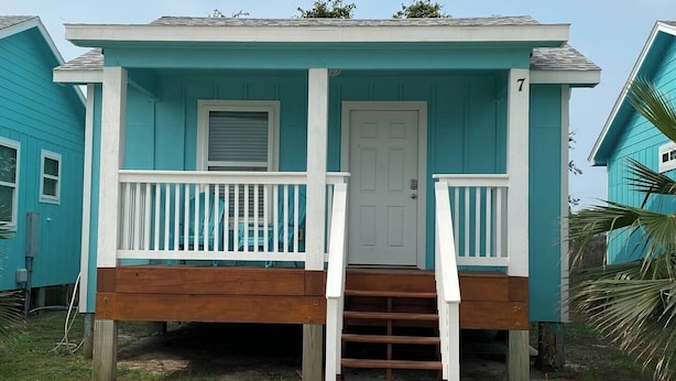 A single-story house with a front porch, a white door, and a small set of stairs leading up to the entrance.