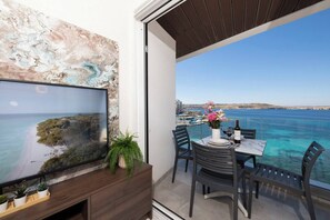 A balcony with a dining table, chairs, and a TV mounted on a wall.