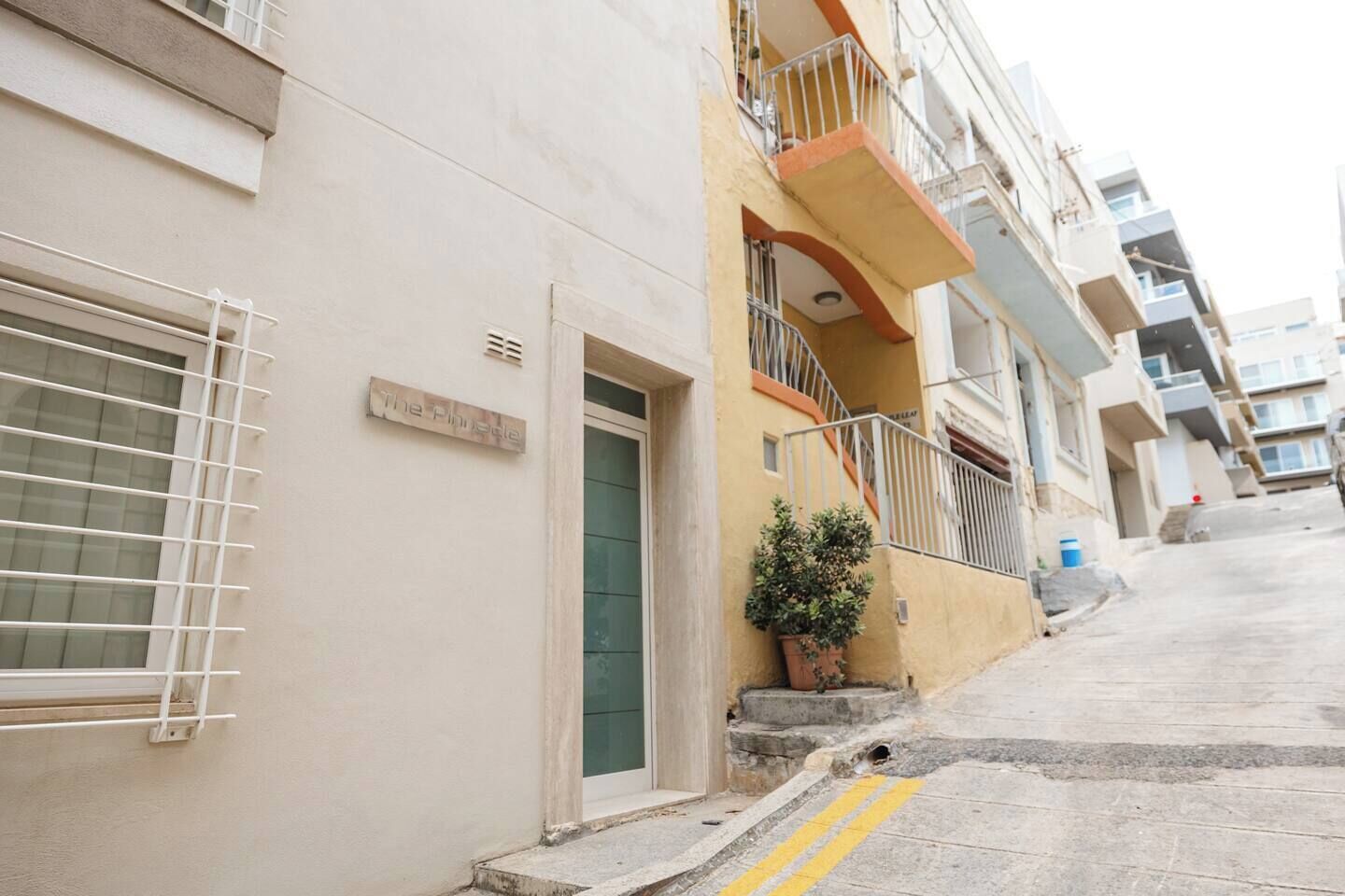 Un edificio residenziale a più piani con balconi, un piccolo vaso con una pianta e una porta ben visibile.