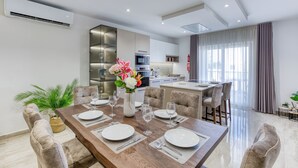 A modern dining area with a wooden table set for six, surrounded by cushioned chairs.