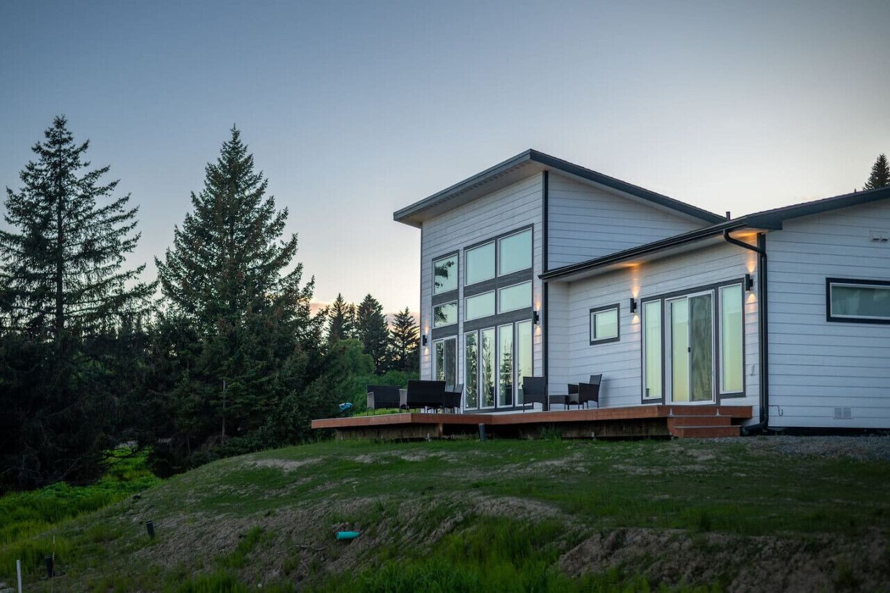 A modern two-story house with large windows and a deck.