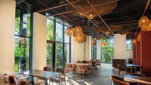 A spacious dining area with natural light, large windows, and modern wooden furniture. - GREENWOOD (Batumi)