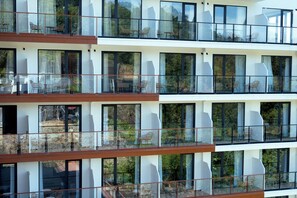 Un hôtel à plusieurs étages doté de balcons, de grandes fenêtres et d’espaces extérieurs aménagés pour s’asseoir.