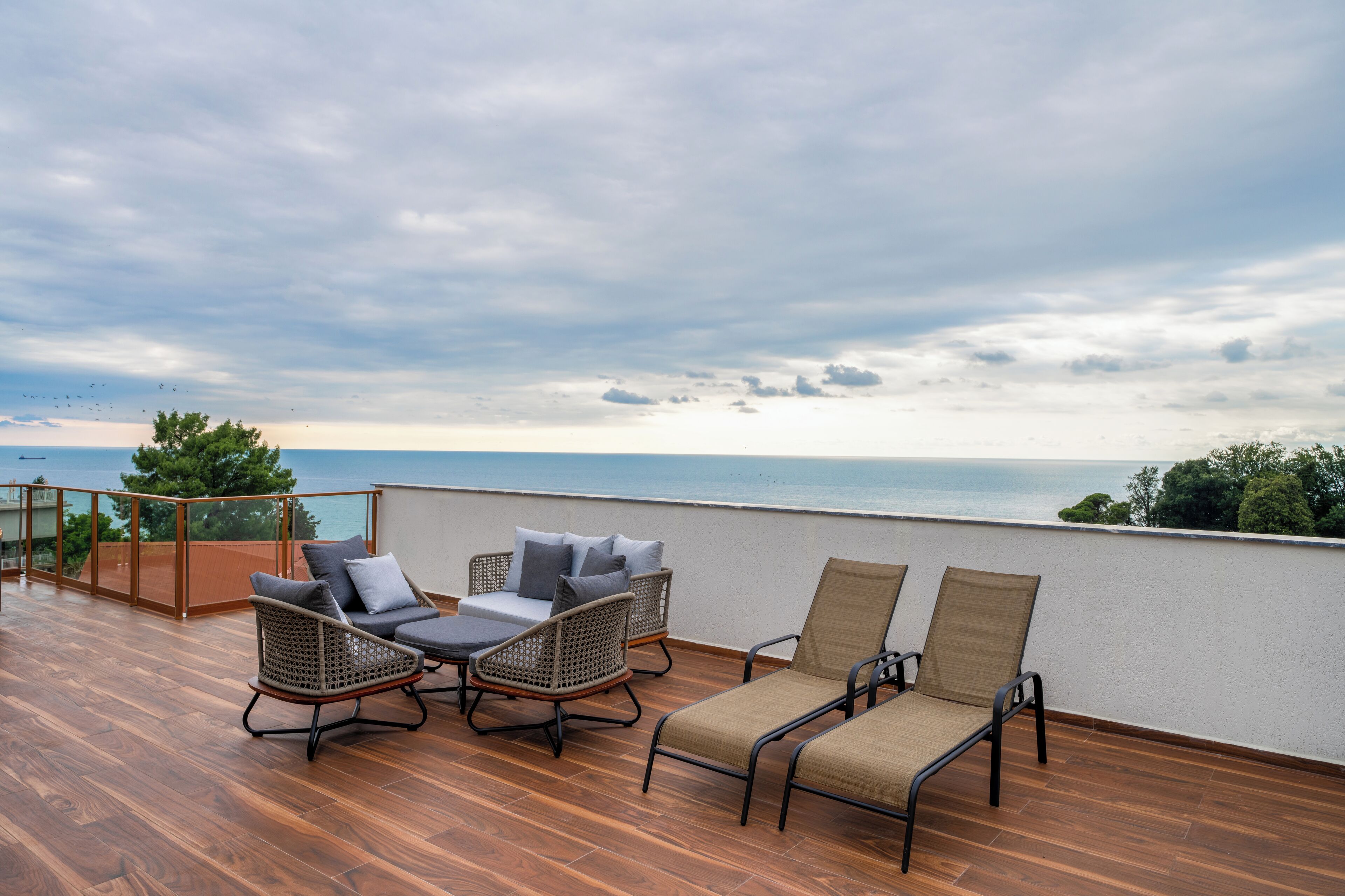 A balcony with wicker chairs and a sofa, overlooking the sea.
