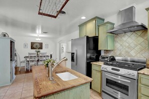 Una cocina con encimera de madera, electrodomésticos de acero inoxidable y armarios verdes.