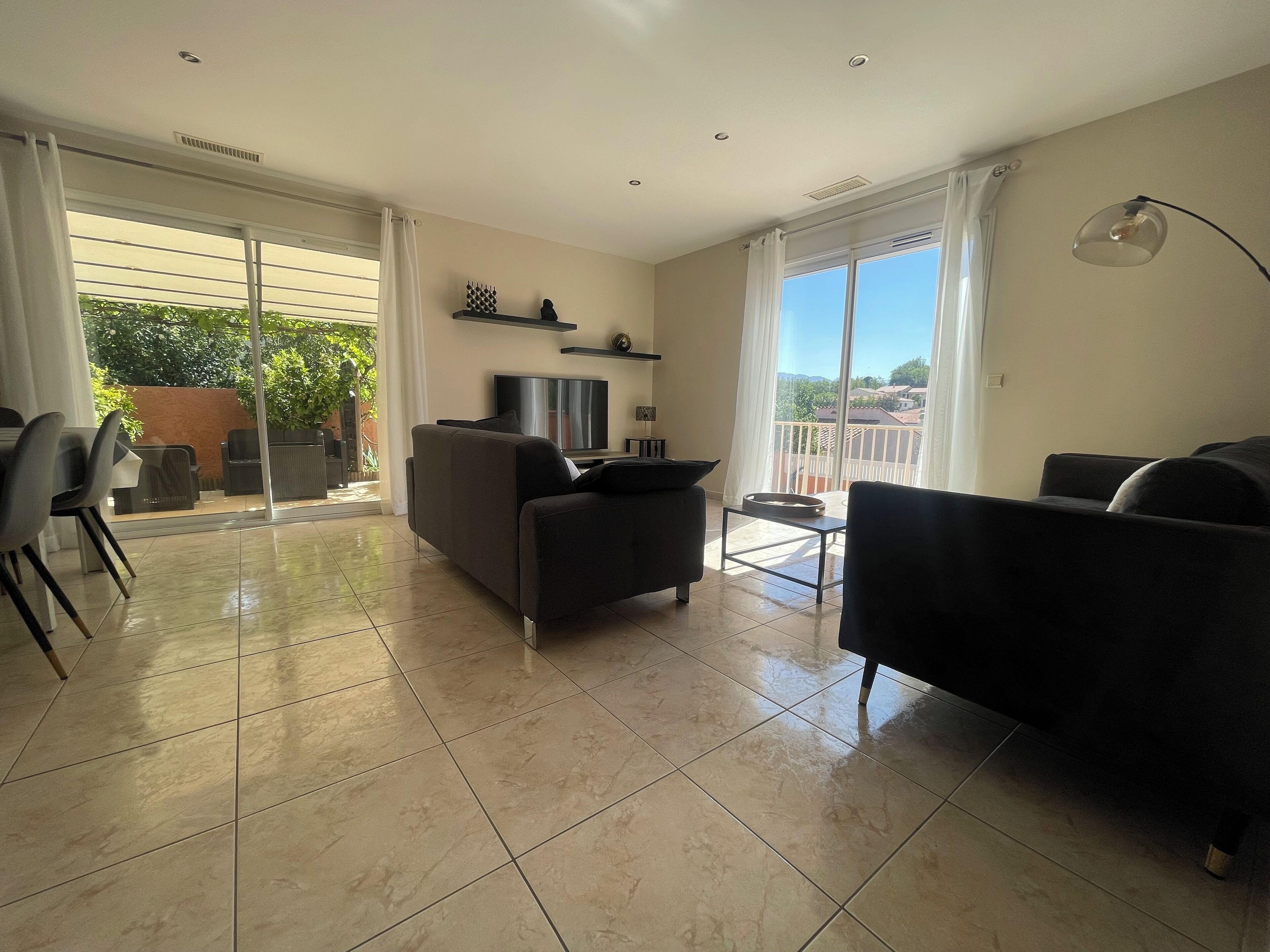 A spacious living area with a sofa, a TV, and a dining table.