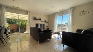 A spacious living area with a sofa, a TV, and a dining table. - Villa Avec Piscine,barbecue,terrasse,proche de la Mer. Idéal Pour les Familles (Banyuls-dels-Aspres)