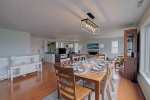 A spacious living area with a dining table set for a meal, a television, and a fireplace.