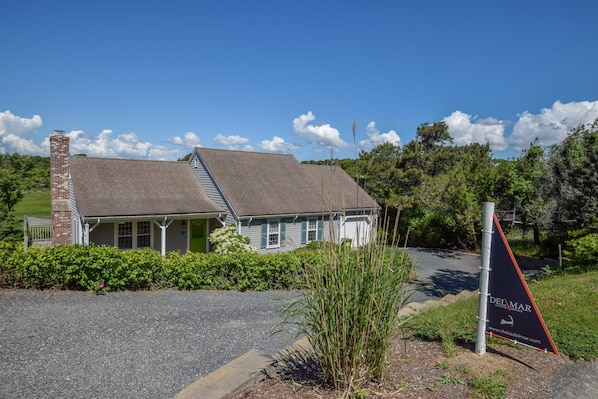 A two-story house with a porch, a chimney, and a signboard for Del Mar Vacation Rentals.