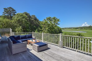 Una terraza con mobiliario exterior, vista a un río y un paisaje boscoso.