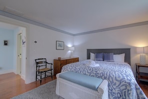 A bedroom with a bed, bedside tables, a chair, a rug, and a door.
