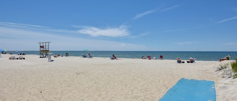 En strand med en livredderstand, parasoller og folk der slapper af.