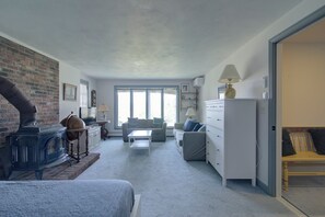 A cozy living room with a fireplace, a sofa, a coffee table, and a television. - Stunning Marsh Views, Near Pleasant Street Beach! (Chatham)