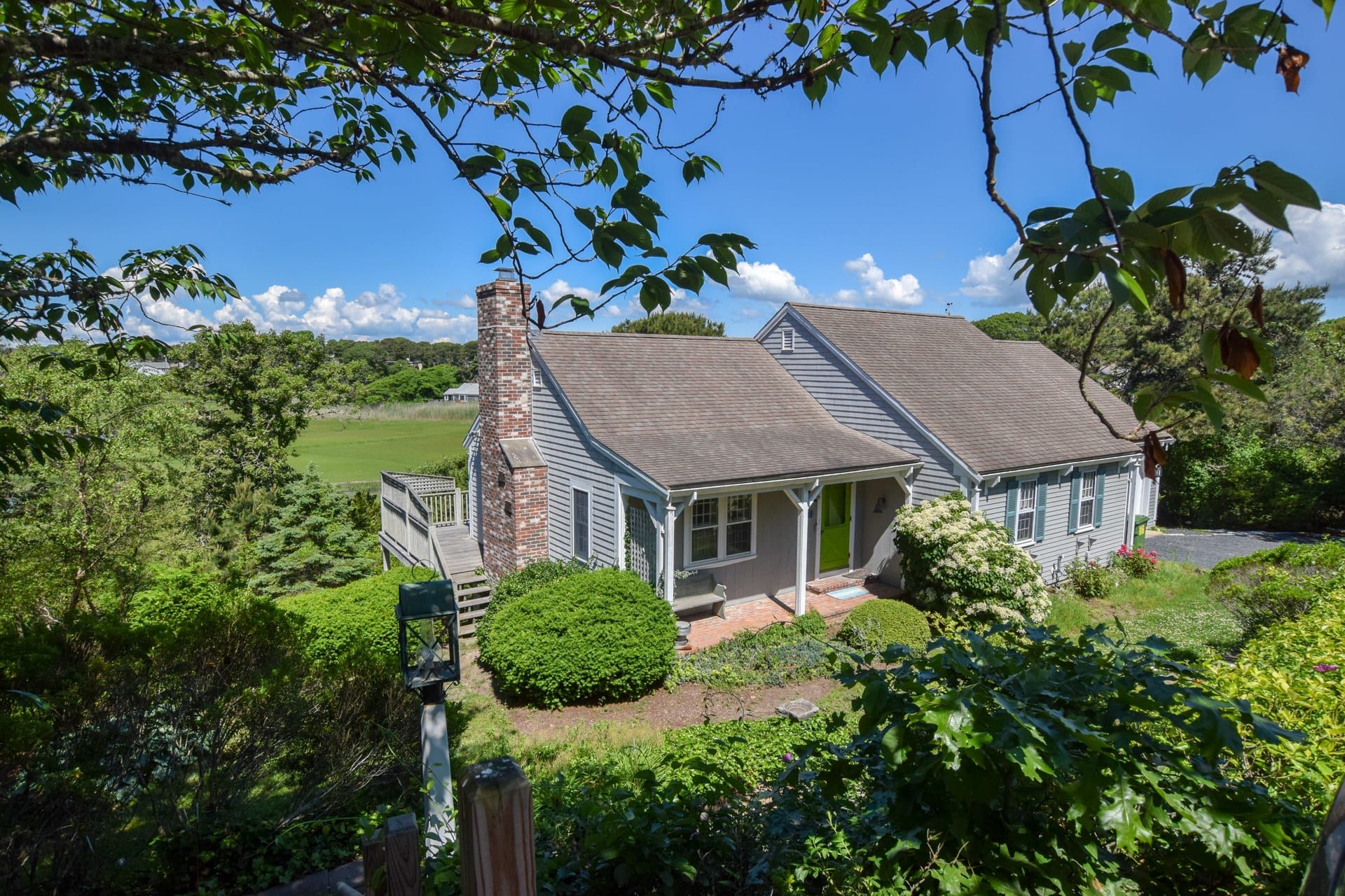 A two-story house with a brick chimney, a covered porch, and a well-maintained garden.