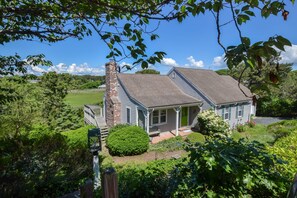 A two-story house with a brick chimney, a covered porch, and a well-maintained garden.
