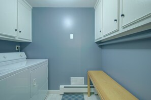 A laundry room with a washing machine, dryer, and a bench. - Stunning Marsh Views, Near Pleasant Street Beach! (Chatham)