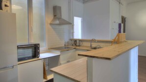 Una cocina moderna con armarios blancos, microondas integrado, estufa e isla de madera con pileta.