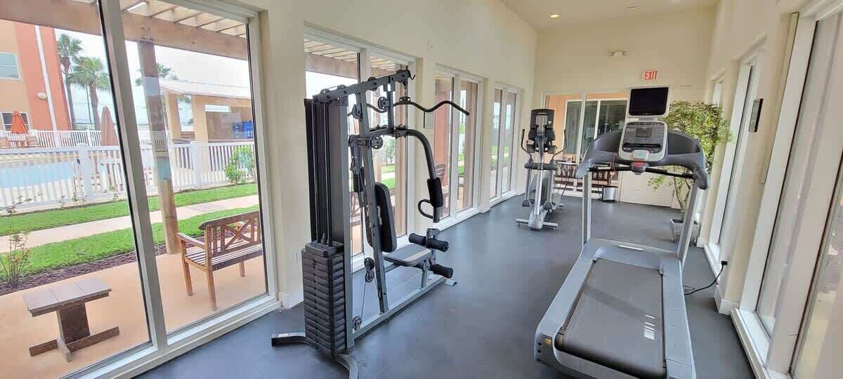 Un gimnasio con equipo de cardio, máquinas de pesas y una cinta de correr.