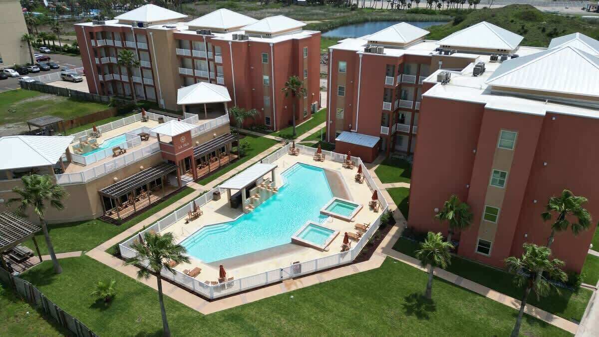 A hotel with a swimming pool, multiple balconies, and a landscaped garden.
