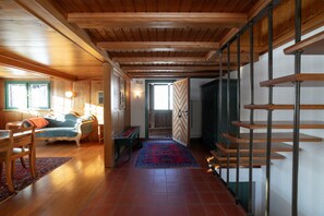 A wooden interior with a staircase, a dining area, and a view through a door.