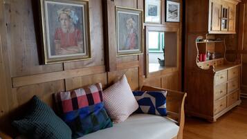 Ein Holzinnenraum mit einer Couch, Kissen und gerahmten Kunstwerken an der Wand.