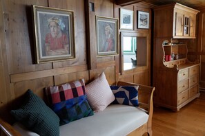 A wooden interior with a sofa, pillows, and framed artwork on the wall.