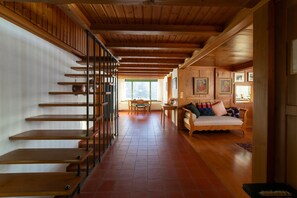 A wooden interior with a staircase, a sofa, and a dining area.
