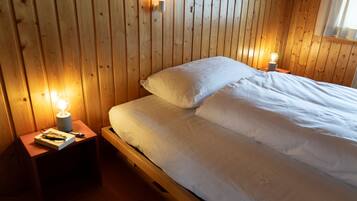 Ein Zimmer mit Holzwänden, einem Bett, zwei Nachttischen und zwei Wandlampen.