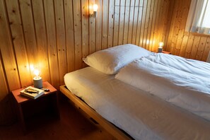 Ein Zimmer mit Holzwänden, einem Bett, zwei Nachttischen und zwei Wandlampen.
