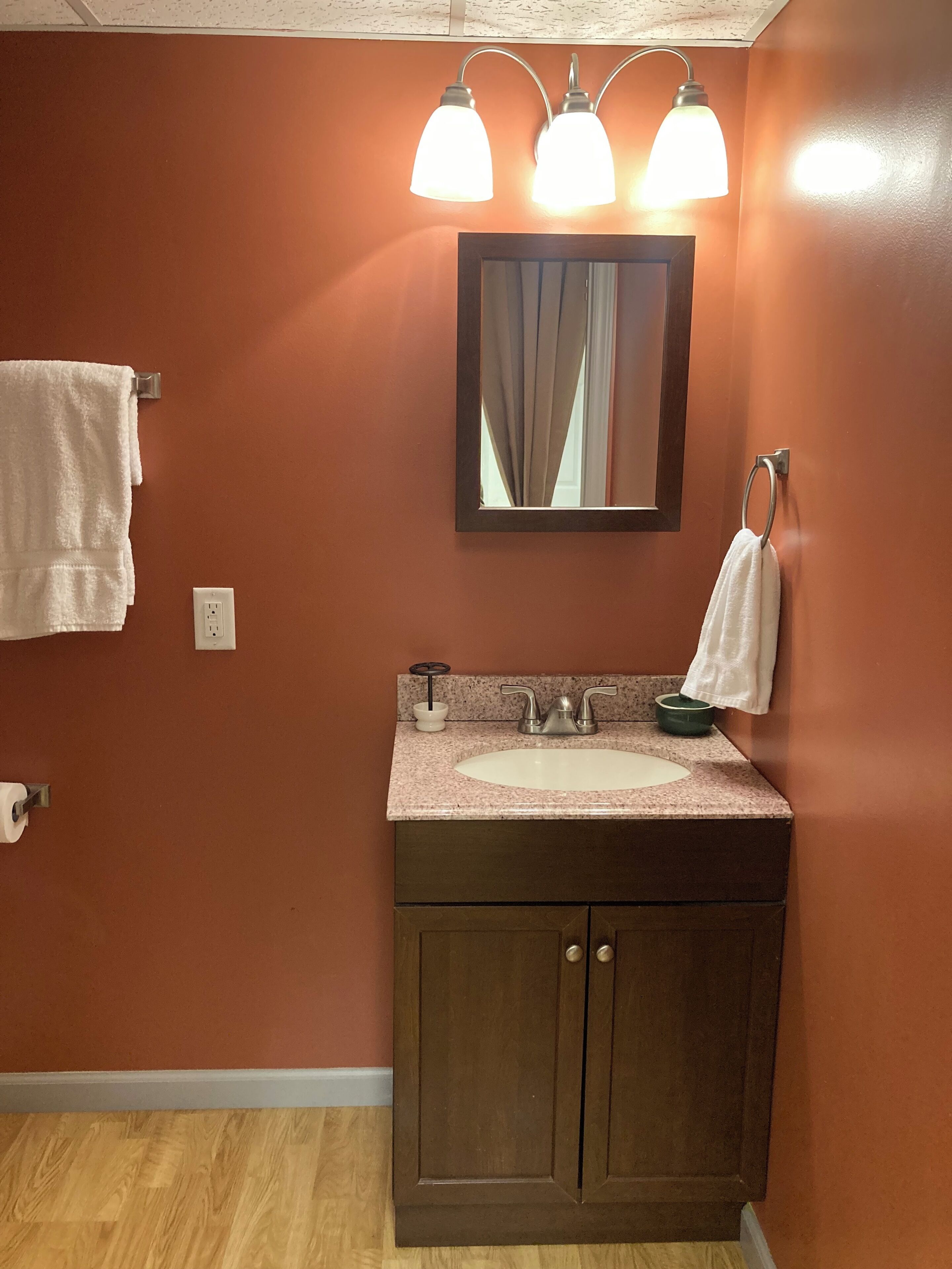 Un baño con tocador de madera, lavabo, espejo y dos luces en la pared.