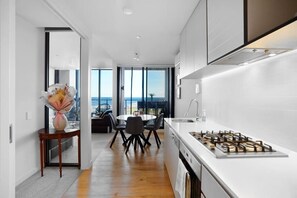 A modern kitchen with a central island, a dining area with a view, and a large window overlooking the ocean.