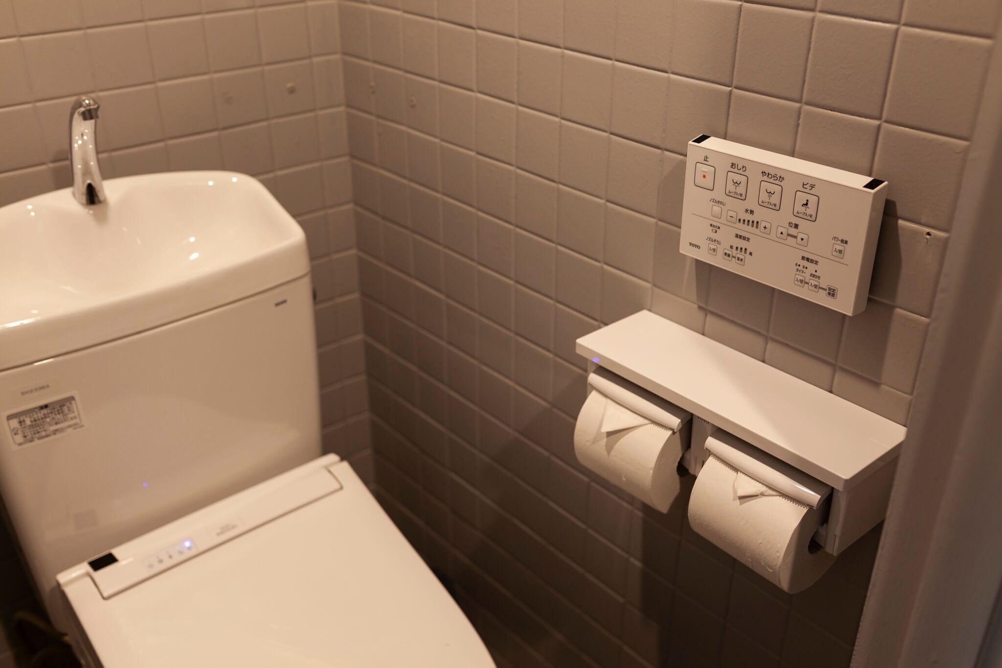 A bathroom with a toilet, a sink, and a toilet paper holder.