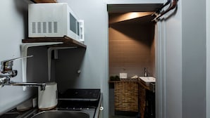 A compact kitchen with a sink, stove, microwave, and a small countertop. - Oyadokinokuniya Isemachi (Nagasaki)