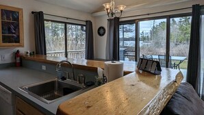 A kitchen with a wooden countertop, a sink, and a window overlooking a deck. - Waterfront close to Traverse City, Kayaks, Row Boat, Firepit, Dog ok, 8pl (Traverse City)