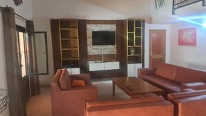 Een woonkamer met een bank, salontafel, televisie en inbouwplanken.