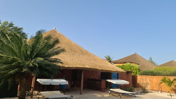 Een resort met rieten hutten, palmbomen en zitgedeeltes buiten.
